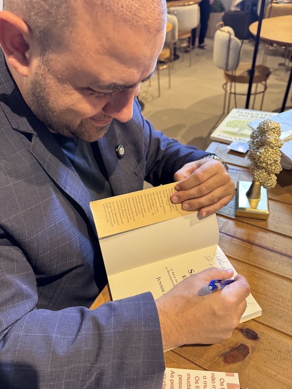 Junior A Rocha sorrindo enquanto assina um exemplar